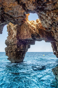 Rock formation in sea against sky