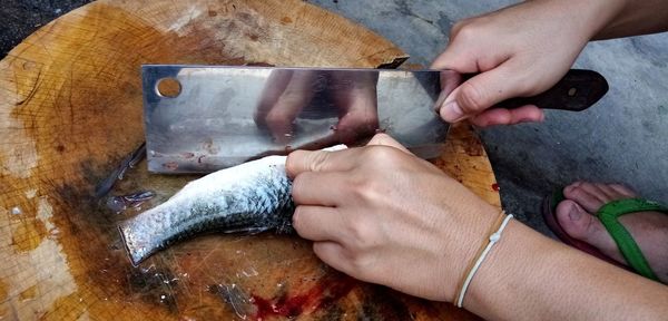 Close-up of hand holding fish on cutting board