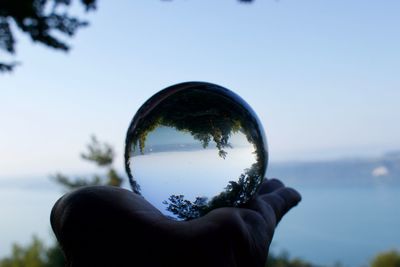 Close-up of hand holding glass against sky