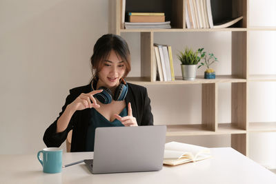 Young woman using phone while sitting on table