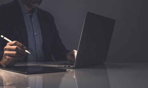 Midsection of man using laptop at table