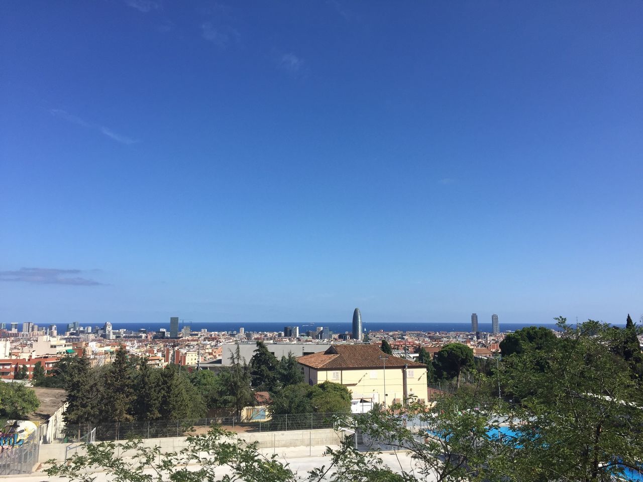 building exterior, architecture, built structure, blue, copy space, clear sky, cityscape, tree, city, sea, high angle view, water, crowded, residential district, residential structure, horizon over water, residential building, town, day, sky