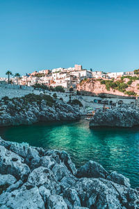 Scenic view of sea by buildings against clear blue sky