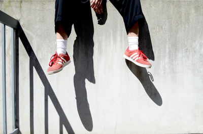 Low section of man sitting on retaining wall