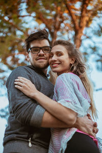 Portrait of smiling young couple against trees