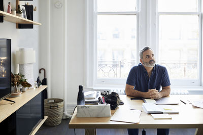 Thoughtful businessman sitting at desk in creative office