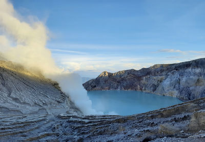 The beautiful view of ijen crater with acid lake, blue sky and dramatic clouds.