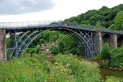 Arch bridge over trees against sky