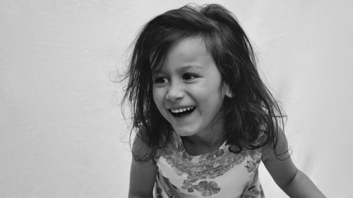Close-up smiling girl against white wall