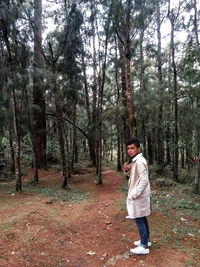 Full length of boy standing in forest