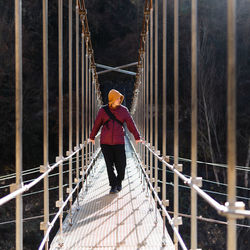 Rear view of man walking on footbridge