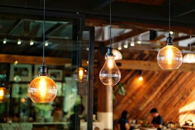 Low angle view of illuminated light bulbs hanging at restaurant