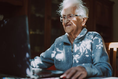 Smiling senior woman using laptop while sitting at home