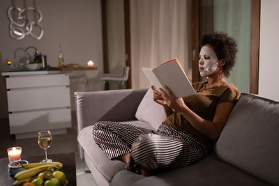 African american woman in sheet mask reading book