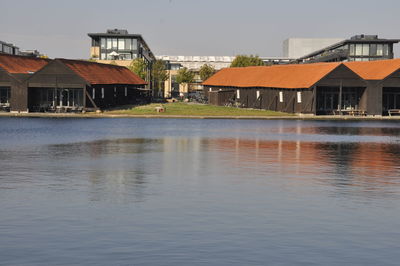 Houses by lake and buildings against sky