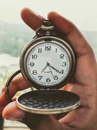 Close-up of hand holding clock