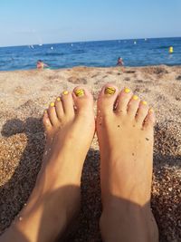 Low section of woman with nail polish at beach