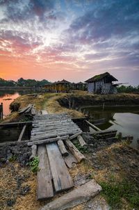 Scenic view of lake by houses against sky during sunset