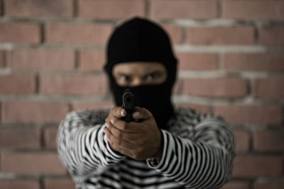 Full length portrait of man holding camera against wall