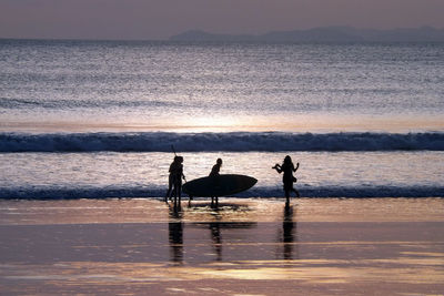 Silhouette of people with surfboard at beach