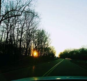 Road amidst trees against sky during sunset