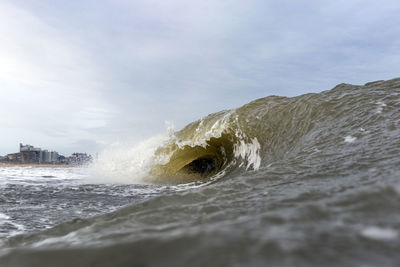 Sea waves splashing on shore against sky