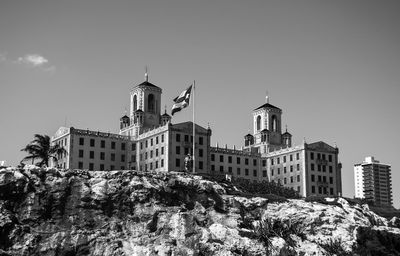 Low angle view of cuban flag waving against hotel nacional de cuba