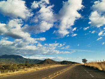 Road leading towards mountains against sky