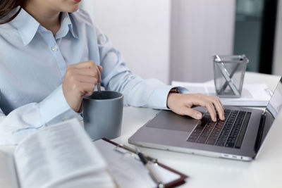 Midsection of doctor using laptop at clinic