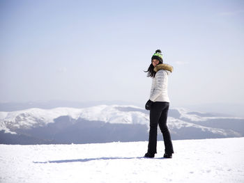 Full length of man standing on snowcapped mountain against sky