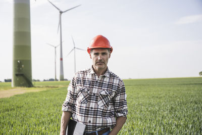 Engineer wearing hardhat standing with tablet pc at field