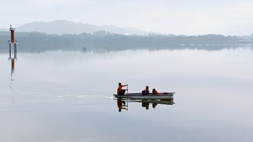 Men in lake against sky