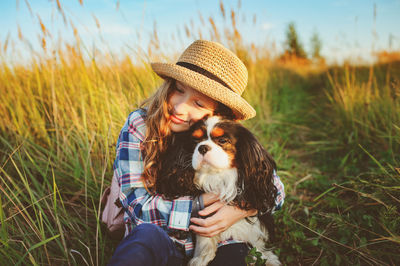 Girl embracing dog while sitting on land