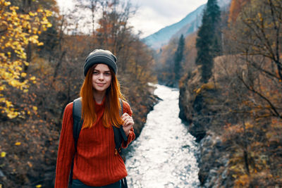 Young woman standing against trees and plants