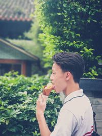 Side view of young man eating food outdoors