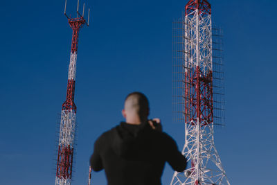 Man standing against communications tower