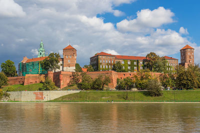 Buildings at waterfront against cloudy sky