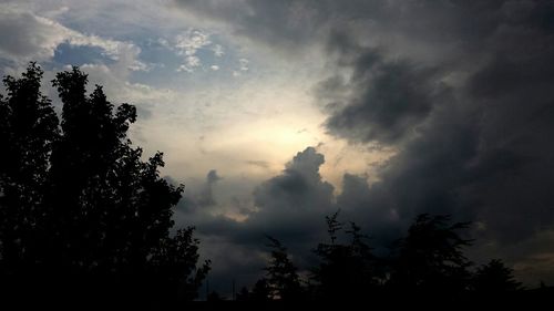 Low angle view of silhouette trees against cloudy sky