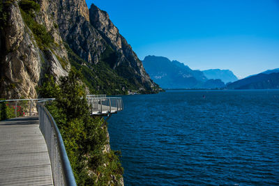 Scenic view of sea and mountains against clear blue sky