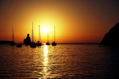 Silhouette sailboats in sea against sky during sunset