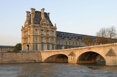 Arch bridge over river against buildings