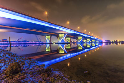 Illuminated bridge over calm sea against sky