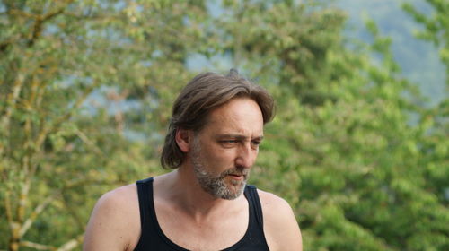 Close-up of thoughtful mature man against trees