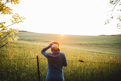 Rear view of woman standing on field against clear sky