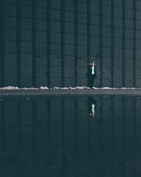 Man standing at lake against wall