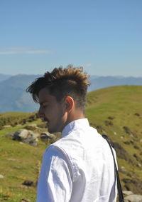 Rear view of a good looking young guy standing in the nature with eyes closed 