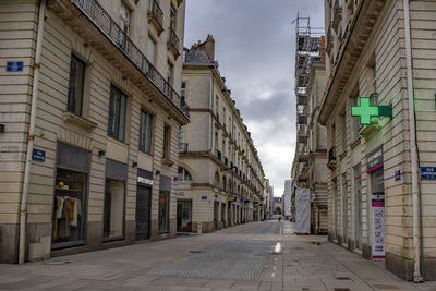 Empty road amidst buildings against sky