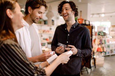 Smiling male friends talking to saleswoman in store