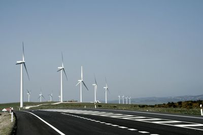 Wind turbines on road against sky