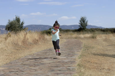 Full length of young woman running on field